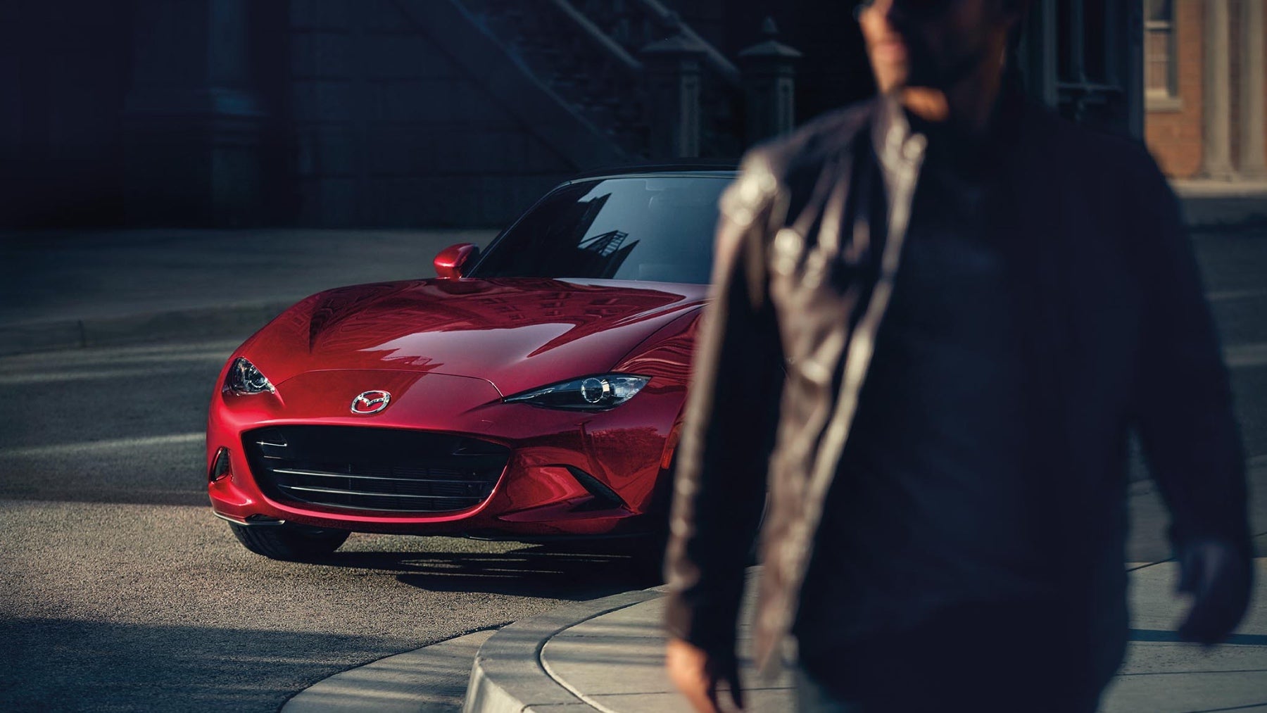 A man walking away from Mazda MX-5 Miata