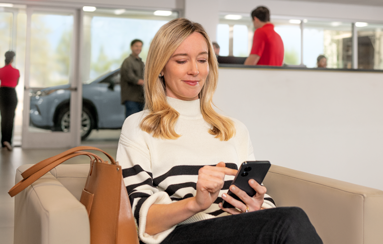 A women is operating mobile at Fitzgerald Mazda of Annapolis Service center Waiting Room